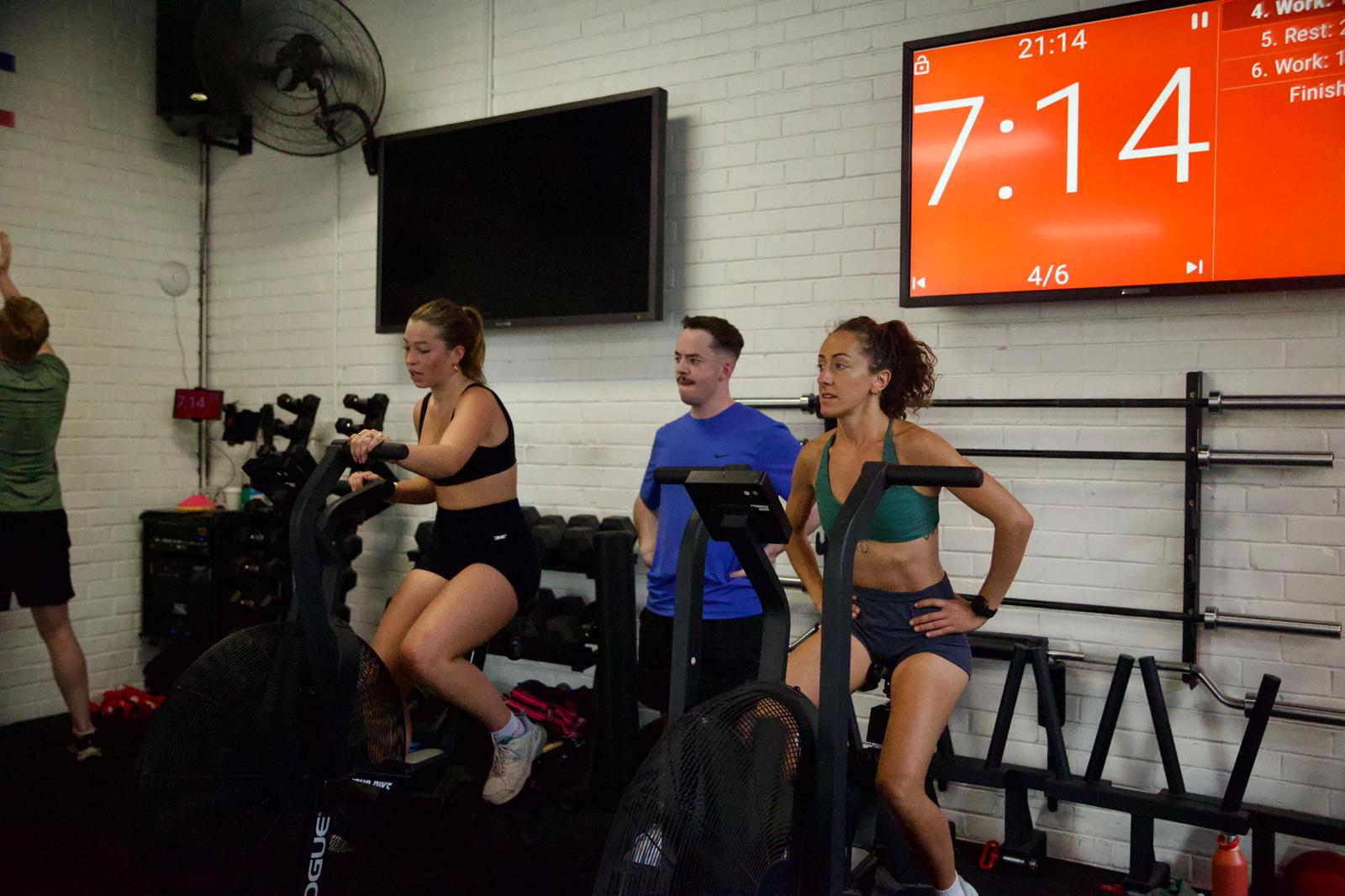 Small group training session on assault bikes with coach and workout timer